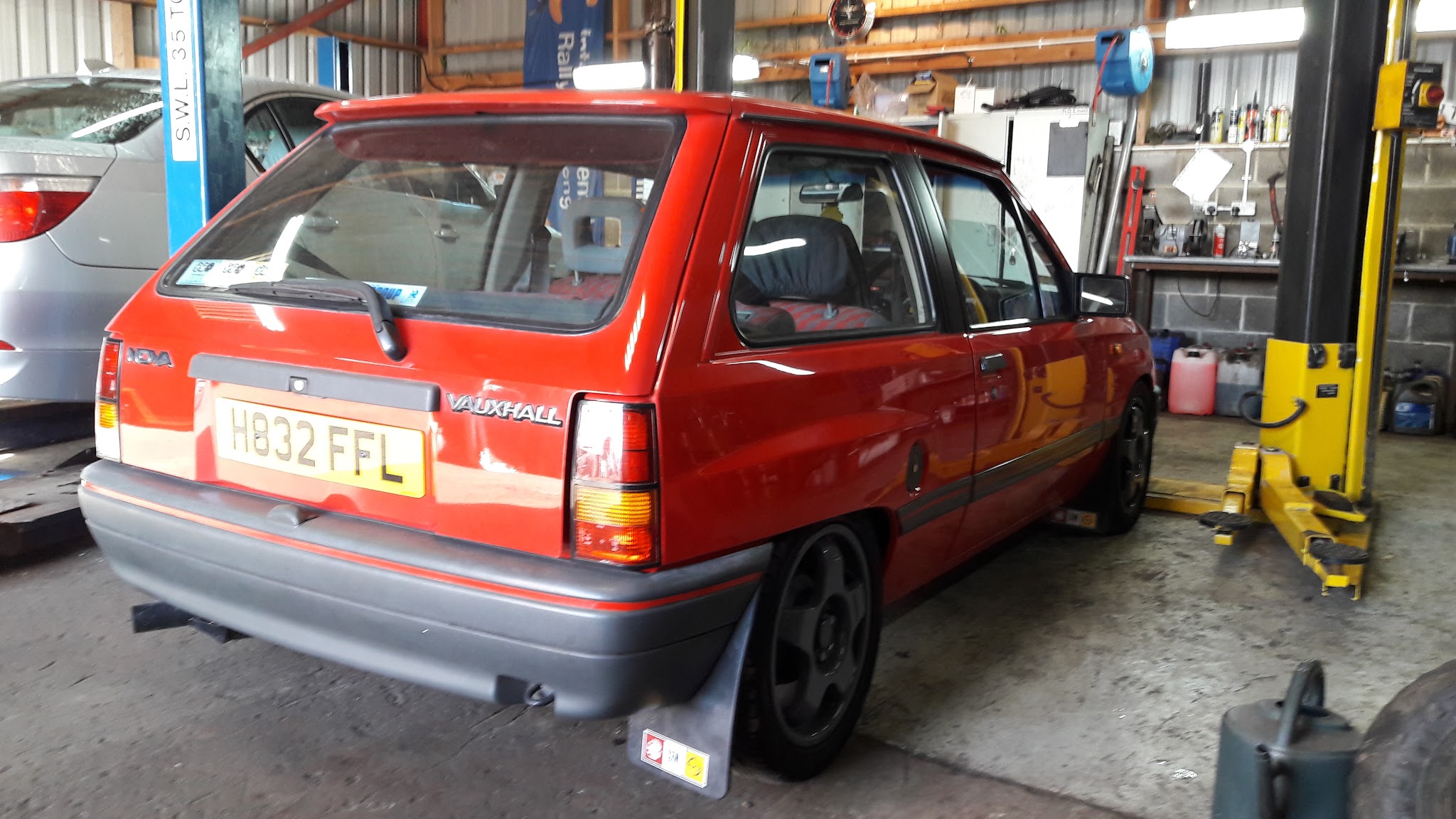 A red classic Vauxhall Nova in the workshop