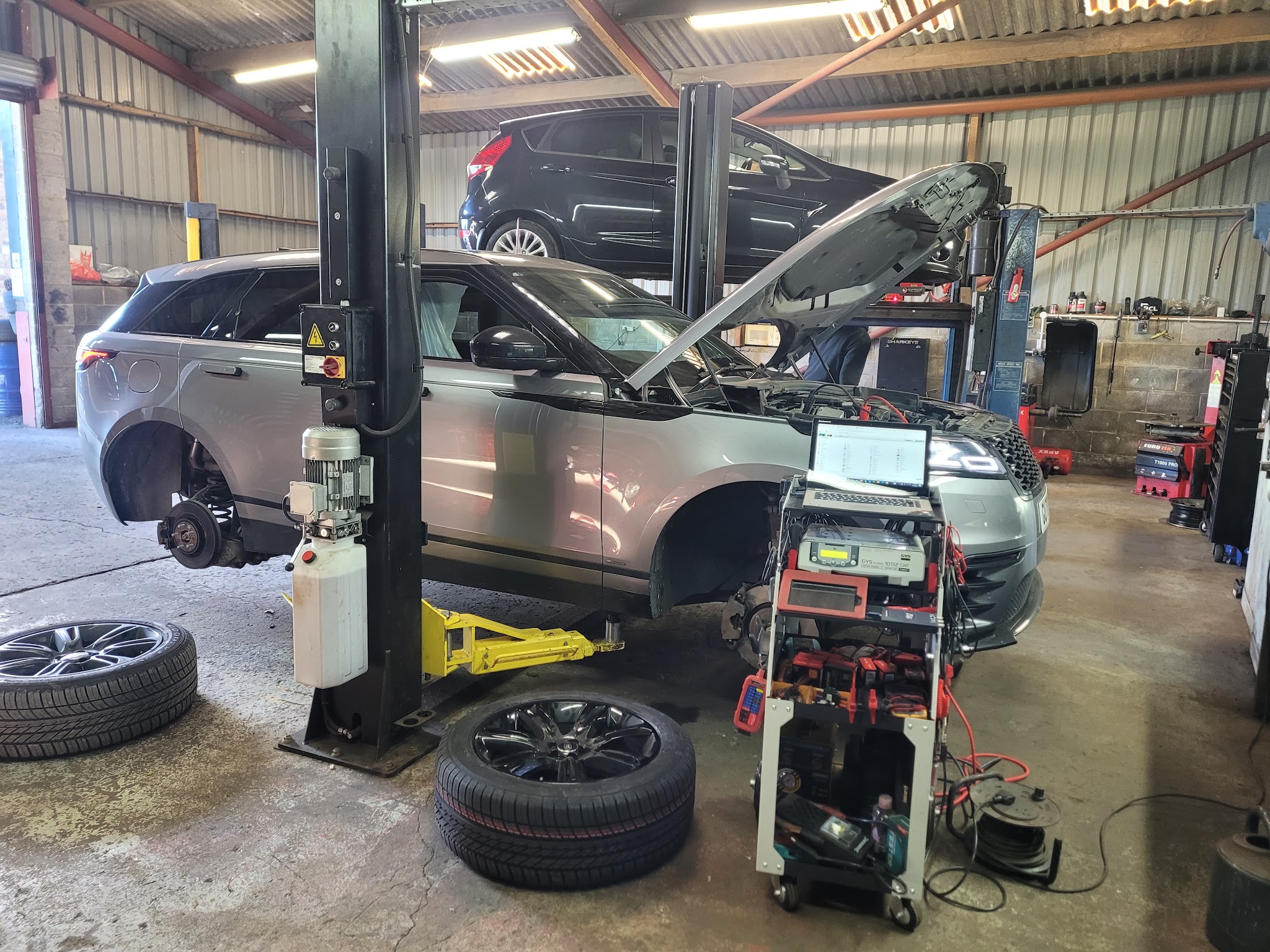 A Range Rover on the lift with its wheels off and the diagnostic trolley alongside