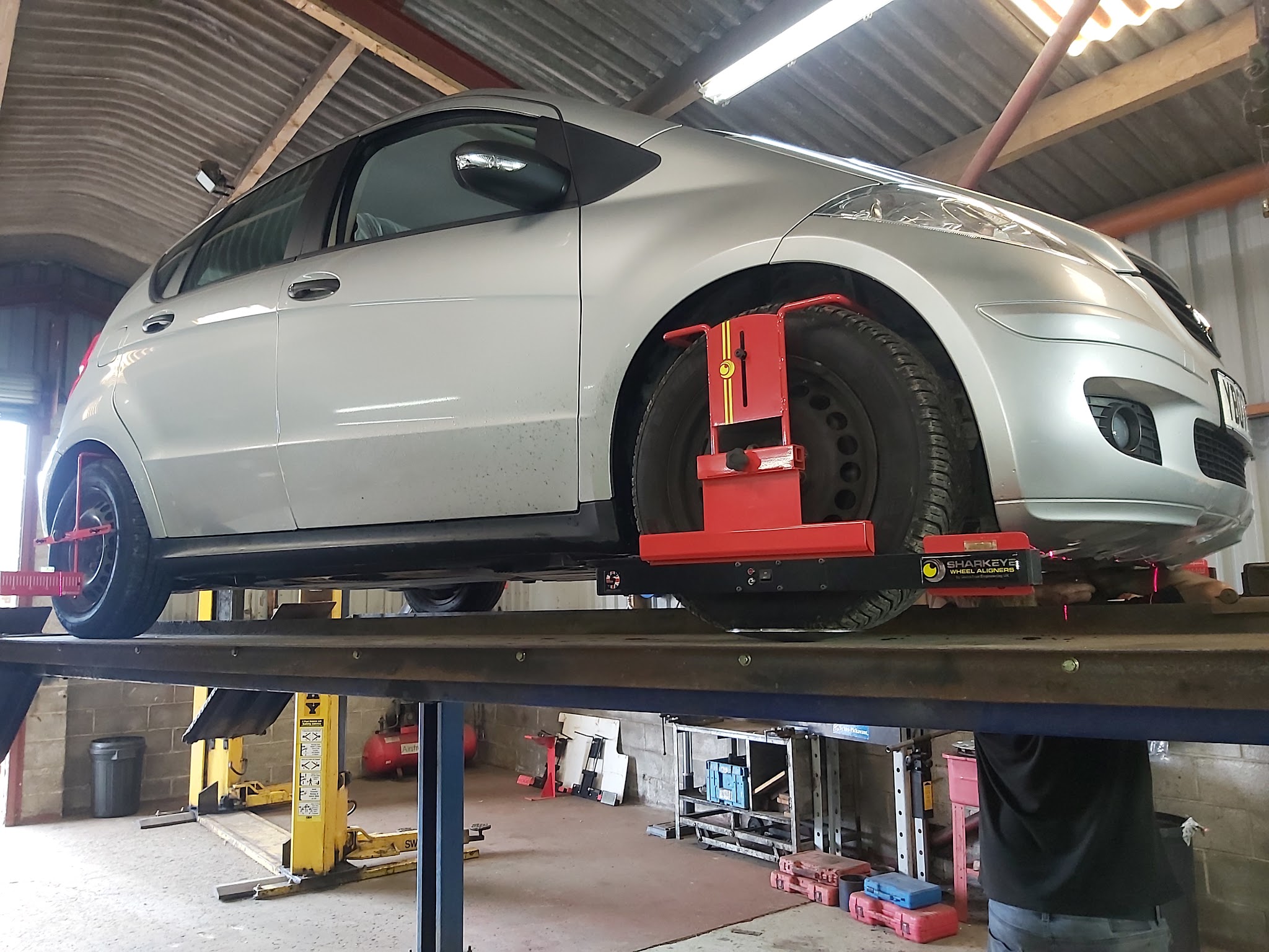 A silver hatchback up on the ramp with wheel clamps fitted
