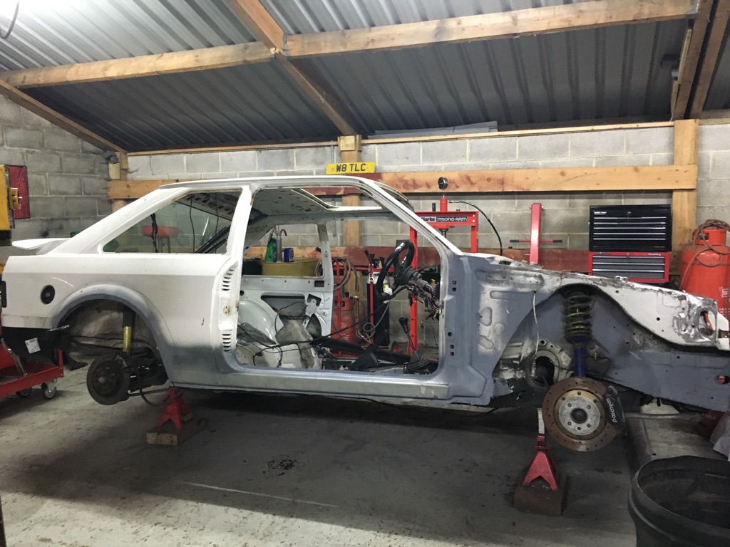 A Ford Escort shell stripped back on axle stands
