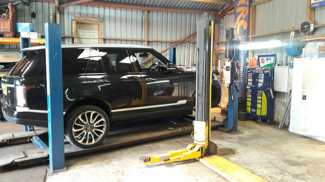 A black Range Rover raised on a two-post lift